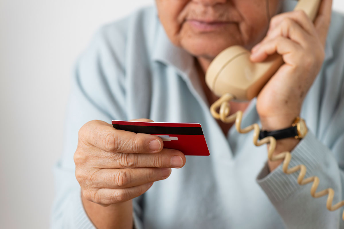 older man talking on the phone and holding his credit card